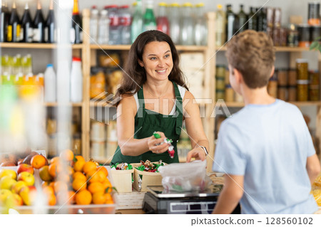 Female seller weighs candies for boy buyer Female seller weighs candies for boy buyer 128560102