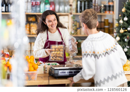 Female employee sells cookies to teen boy on Christmas Eve. 128560126