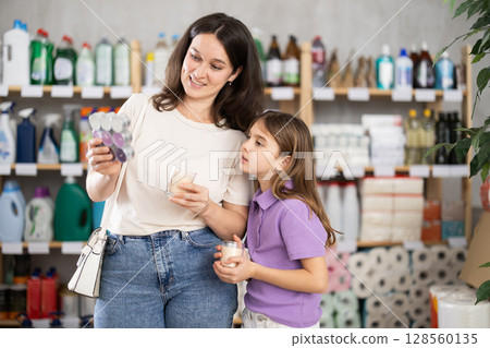 Woman with daughter choose scented candles in store Woman with daughter choose scented candles in store 128560135