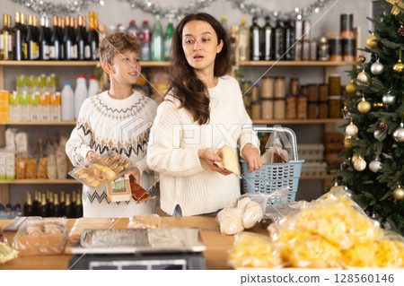Adult woman with son choosing products in grocery store 128560146