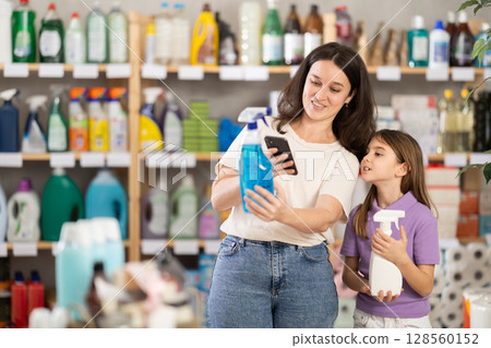 Woman with daughter scanning qr code for spray Woman with daughter scanning qr code for spray 128560152