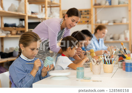 Girl paints ceramic dishes 128560158