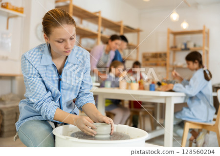 Girl working at a potter's wheel Girl working at a potter's wheel 128560204