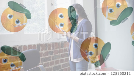 Multiple sick face emojis moving against woman wearing face mask talking on smartphone at office Multiple sick face emojis moving against woman wearing face mask talking on smartphone at office 128560211