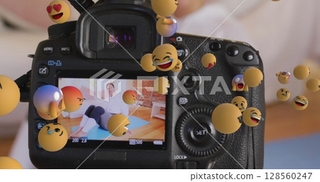 Image of emojis over camera viewer with female fitness vlogger exercising at home Image of emojis over camera viewer with female fitness vlogger exercising at home 128560247