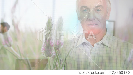 Image of glowing light over portrait of happy senior man and meadow 128560320