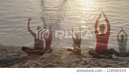 Image of glowing light over senior women practicing yoga by seaside 128560324