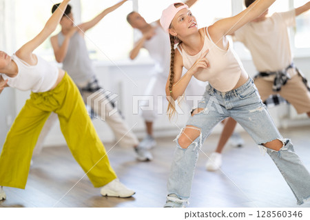 Stylishly dressed teenagers learn to dance hip-hop and breakdance in dance studio 128560346
