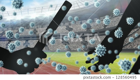 Covid-19 cells floating against silhouette of hand passing a baton against sports stadium 128560495