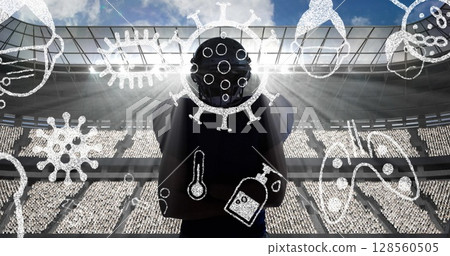 Covid-19 concept icons against silhouette of male rugby player against sports stadium 128560505