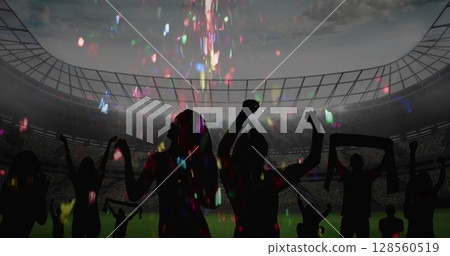 Colorful confetti falling over silhouette of fans cheering and sports stadium in background 128560519