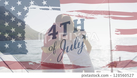 Image of text july 4th with american flag billowing over back view of couple embracing by sea 128560527