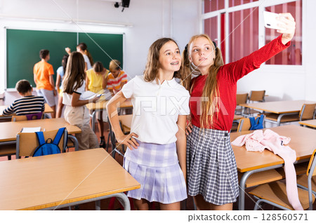 Cheerful girls classmates taking funny selfie with phone during break 128560571