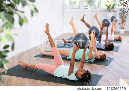 African girl participates in group lesson with softball, modern sport in studio. 128560859