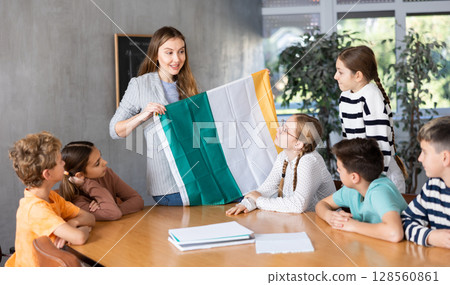 Teacher showing Ireland flag to group of schoolchildren Teacher showing Ireland flag to group of schoolchildren 128560861