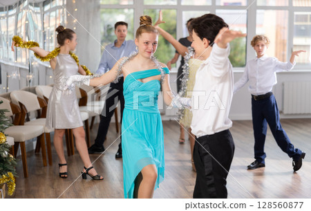 Teen boy and girl dancing waltz in couple during lesson at studio in New Year atmosphere 128560877