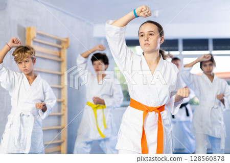 Children students repeat position and perform sequence of punches and painful techniques kata 128560878