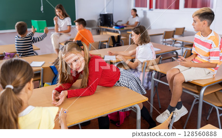 Girl and boy are sitting at the desk and talking about life in classroom Girl and boy are sitting at the desk and talking about life in classroom 128560888