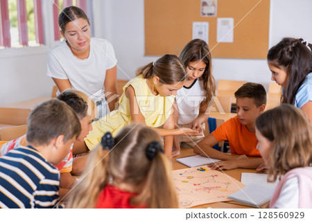 Kids and female teacher playing together educational board game in classroom at school 128560929