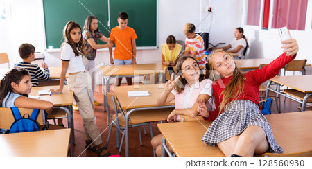 Two girls taking selfies in classroom during recess 128560930