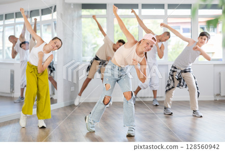 Teenage girl practicing hip hop slide moves in training hall 128560942