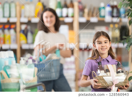 Girl holding a set of care shampoos and shower gels in her hands 128560943