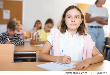 Portrait of school girl who writing exercises at lesson in school Portrait of school girl who writing exercises at lesson in school 128560944