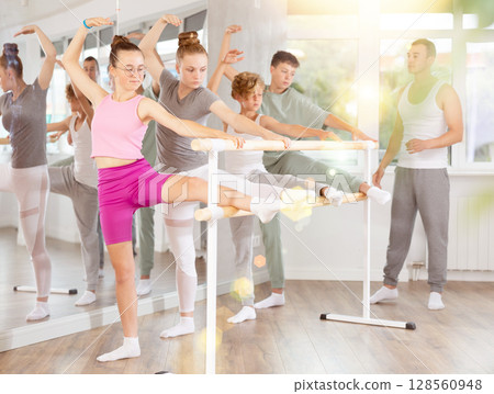 Ballet pose grand batman - girls and boys at a choreography lesson are learning ballet movements in studio Ballet pose grand batman - girls and boys at a choreography lesson are learning ballet movements in studio 128560948