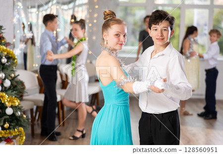 Teen boy and girl dancing waltz in couple during lesson at studio in New Year atmosphere Teen boy and girl dancing waltz in couple during lesson at studio in New Year atmosphere 128560951