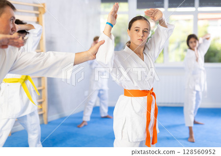 Teacher corrects pupil pose posture position of body, hands, legs during karate classes Teacher corrects pupil pose posture position of body, hands, legs during karate classes 128560952