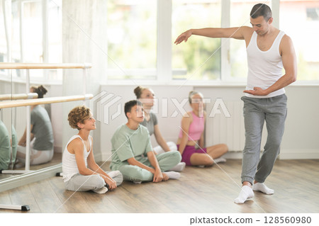 Teen visitors to choreographic class, observe professional rendering of dance performances couch Teen visitors to choreographic class, observe professional rendering of dance performances couch 128560980
