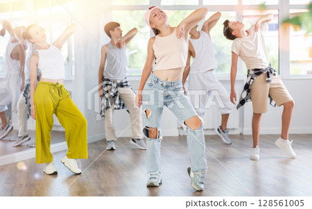 Girl in baseball cap with two hair pigtails with group of teenage friends, learn to dance hip hop 128561005