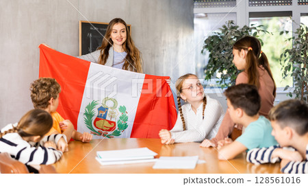 Teacher showing Peru flag to group of schoolchildren 128561016