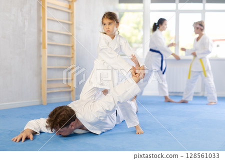 Preteen girl in kimono practicing painful armlock in sparring with father Preteen girl in kimono practicing painful armlock in sparring with father 128561033