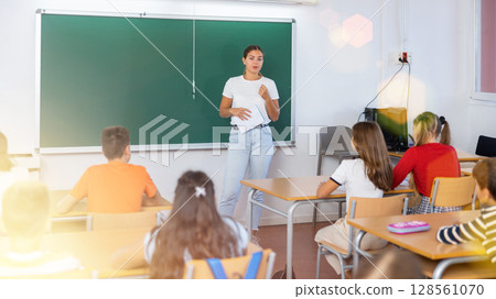 Teacher explaining subject to schoolgirls and schoolboys Teacher explaining subject to schoolgirls and schoolboys 128561070