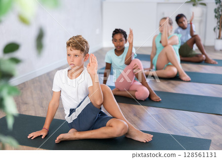 In sport studio with group of friends, boy perform Lord of Fishes asana, Ardha Matsyendrasana 128561131