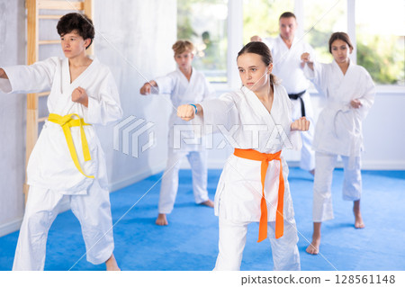Children in kimono standing in fight stance during group karate training in gym 128561148