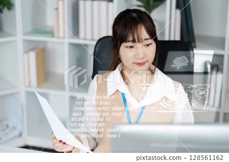 Young Professional Woman Analyzing Data on a Computer in a Modern Office Environment 128561162