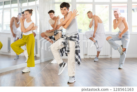 Teen guy together with group of teenage friends, learn to dance hip hop in choreographic hall. Teen guy together with group of teenage friends, learn to dance hip hop in choreographic hall. 128561163