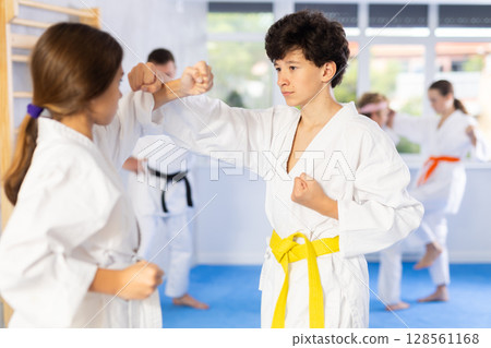 Teenagers girl and boy in kimono sparring together in gym during karate training 128561168