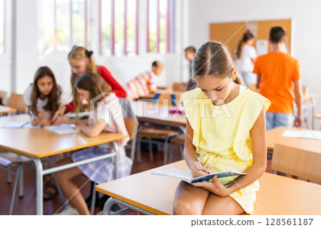 Portrait of clever schoolgirl with copybook in classroom 128561187