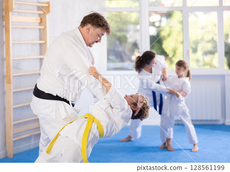 Father sparring with preteen son during martial arts training session 128561199