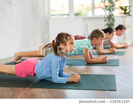 Confident mom, Dad, son and daughter perform power plank pose, Kumbhakasana Confident mom, Dad, son and daughter perform power plank pose, Kumbhakasana 128561297
