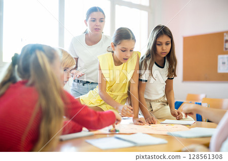 Children and teacher playing together educational board game in class 128561308