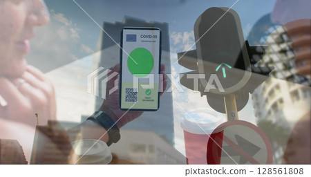 Composition of woman holding a smartphone with qr code on screen against traffic signal light Composition of woman holding a smartphone with qr code on screen against traffic signal light 128561808