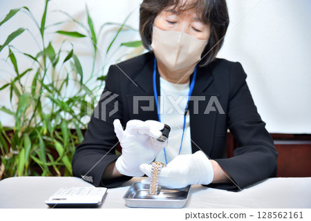 評估師正在評估一隻手錶的圖片 評估師正在評估一隻手錶的圖片 128562161