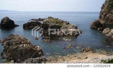The Sea of Japan and the orange rock lilies blooming on the oddly shaped rocks of the scenic Sasagawa Nagare River 128562639