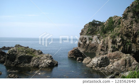 The Sea of Japan and the orange rock lilies blooming on the oddly shaped rocks of the scenic Sasagawa Nagare River 128562640