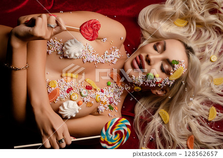 Woman adorned with colorful candy bodyart poses playfully in a studio setting Woman adorned with colorful candy bodyart poses playfully in a studio setting 128562657