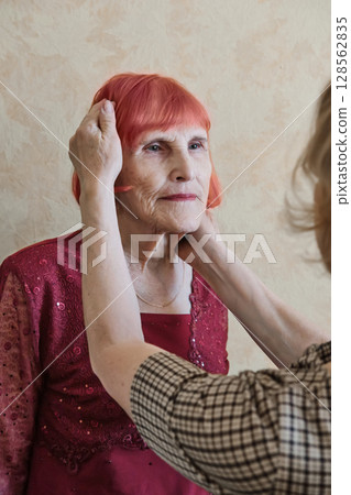 Elderly caucasian woman in red outfit with hair styled by daughter Elderly caucasian woman in red outfit with hair styled by daughter 128562835